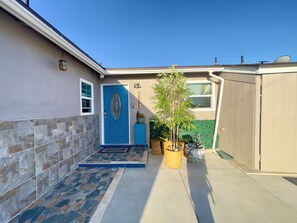 A residential entrance with a blue door, a mailbox, and a small garden area with potted plants. - San Diego Family Getaway /Private Fire Pit (San Diego)
