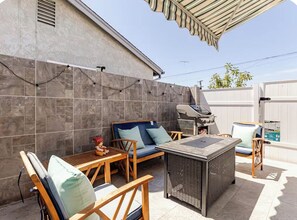Un patio exterior con una parrilla, zona de estar y una pared de azulejos.