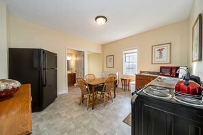 A compact kitchen with a refrigerator, stove, microwave, and dining area. - 315 Cozy 2BR – free parking Medium & Long term (Indianapolis)