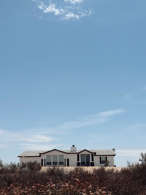 A modern two-story house with a flat roof, large windows, and a satellite dish. - Spacious 4 Bedroom home on an 80 acre horse ranch- 15 minutes from Wine Country (Hemet)
