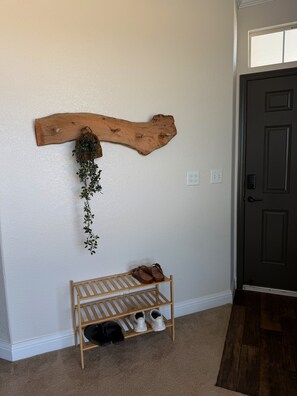 Un pasillo con un zapatero de madera, un adorno de madera en la pared y una puerta.