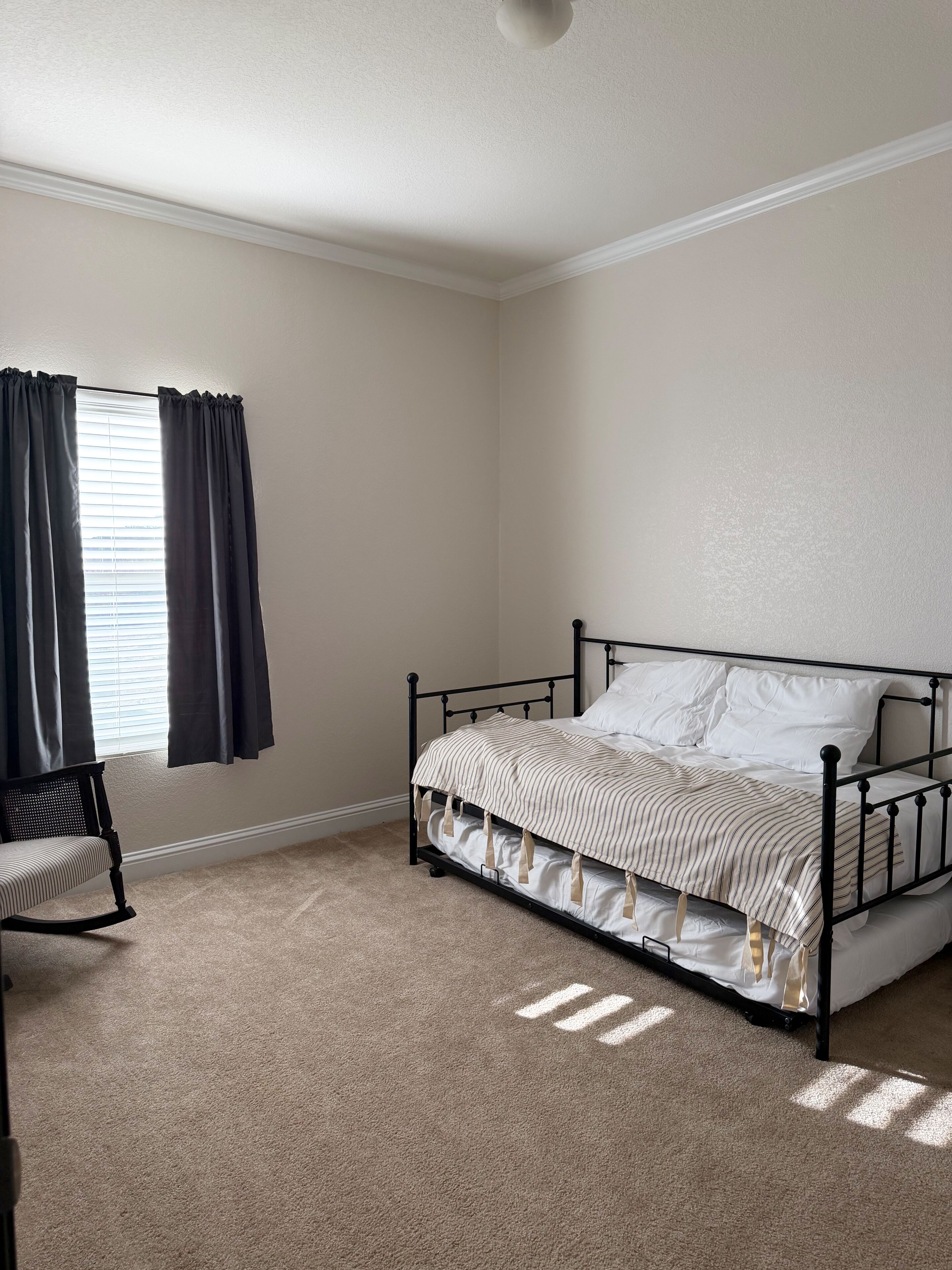 Une chambre à coucher avec un lit, une chaise et une fenêtre avec des rideaux.