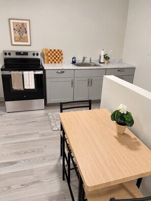 Eine moderne Küche mit Backofen, Spüle und Essbereich mit Tisch und Stühlen.