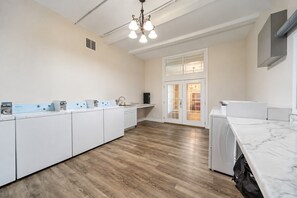 Una cocina moderna con armarios blancos, encimera de mármol y lavadora integrada.