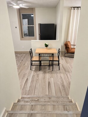 Ein Essbereich mit Tisch und Stühlen, einer Kübelpflanze und einem Fernseher an der Wand.
