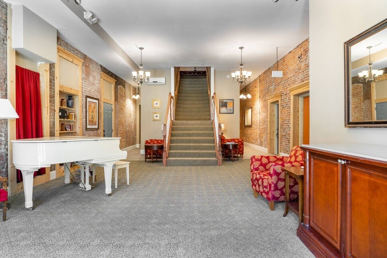 Un vaste salon agrémenté d’un magnifique piano à queue, d’un escalier et d’un canapé recouvert d’un tissu à motifs.