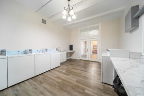 Cozinha moderna com armários brancos, bancada de mármore e piso de madeira.