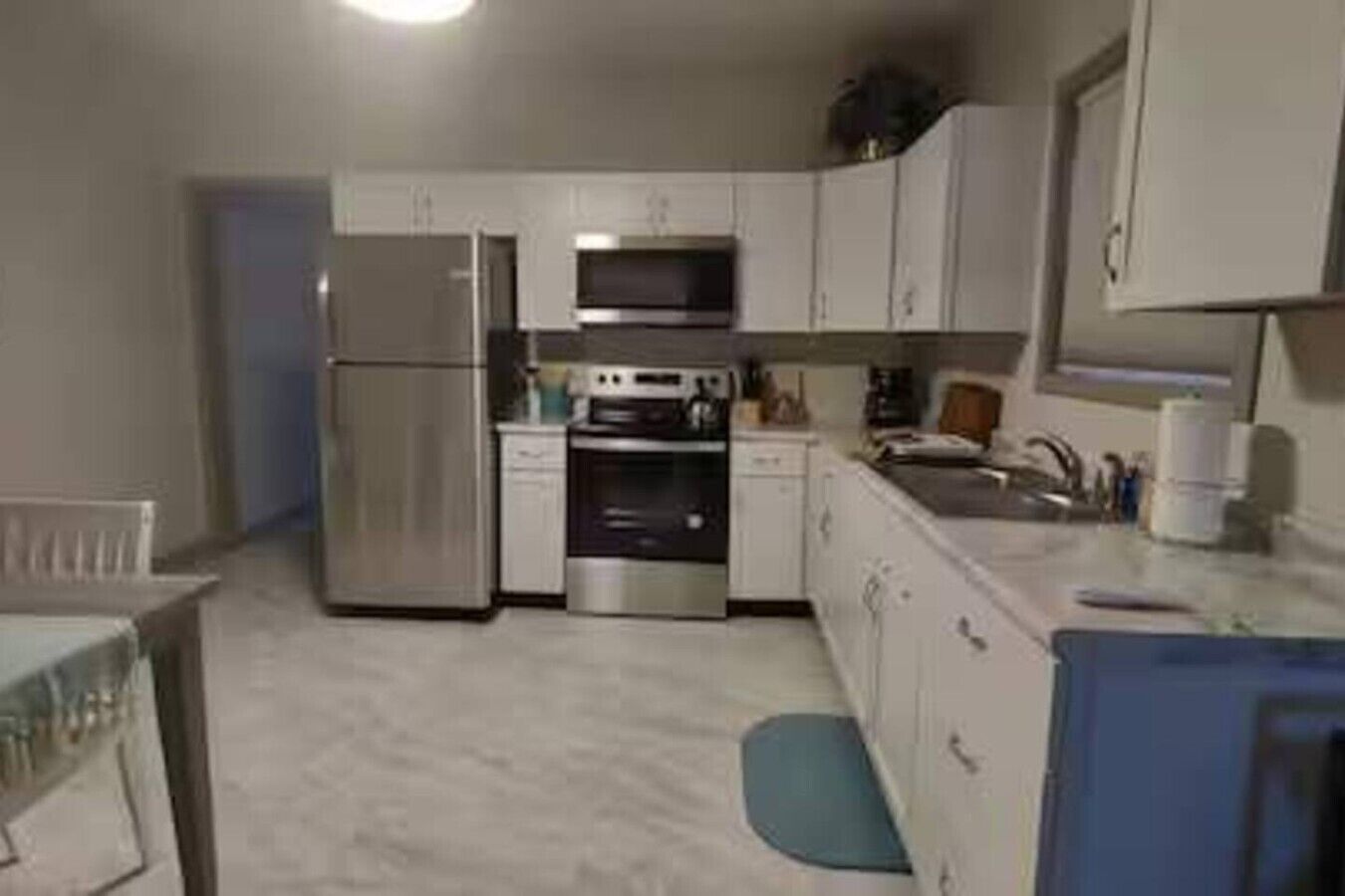 Eine kleine Küche mit Kühlschrank, Backofen, Mikrowelle und Spüle.