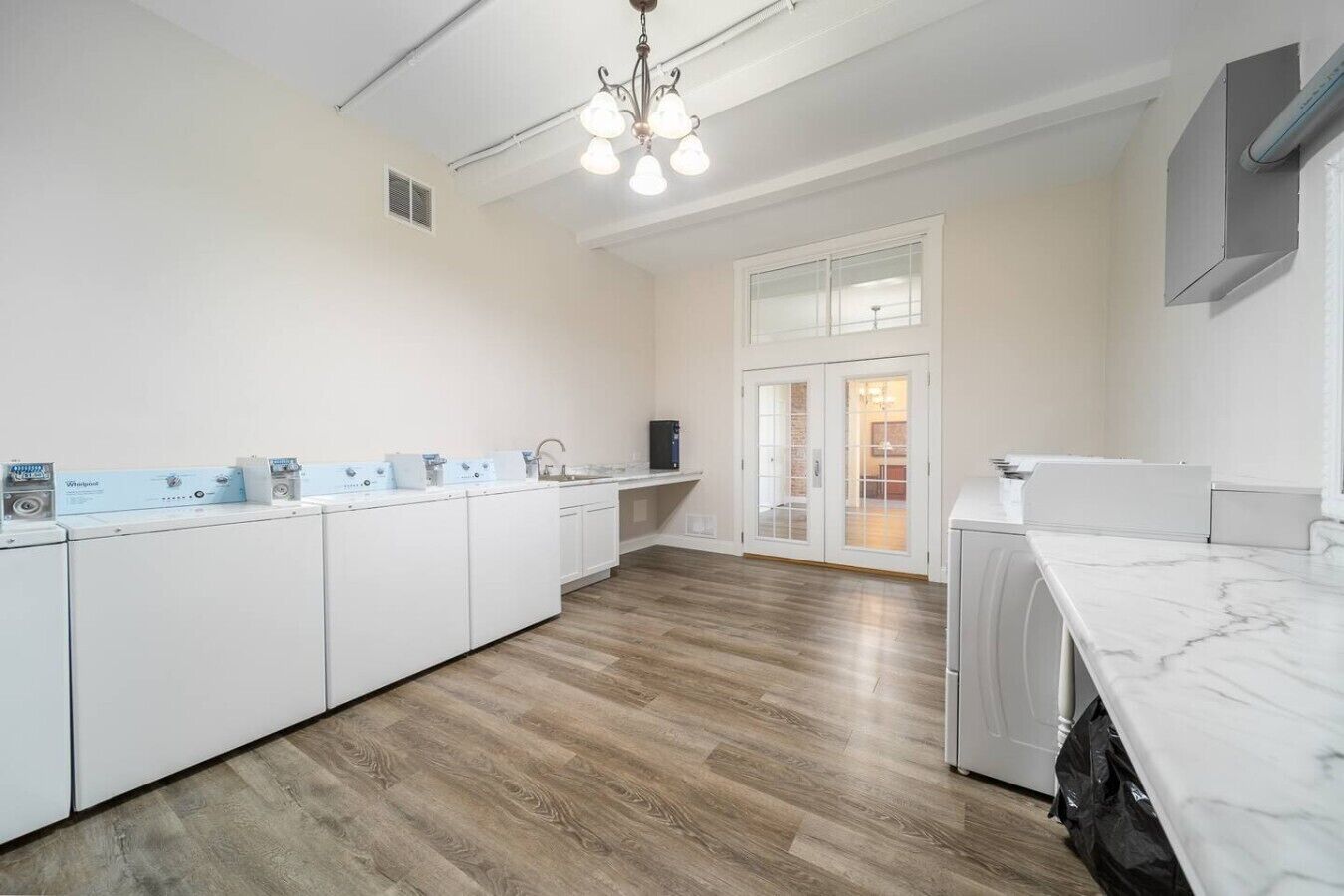 Une cuisine moderne avec des meubles blancs, un plan de travail en marbre et un plancher en bois.