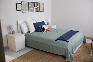 Ein Schlafzimmer mit einem Bett, Nachttischen, einer Lampe und gerahmten Bildern an der Wand.