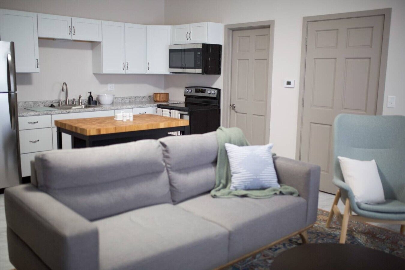 Een gezellig, compact leefruimte met een kitchenette, een bank, een stoel en een eettafel.