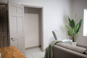 Ein Zimmer mit geschlossener Tür, einem Stuhl, einem Tisch und einer Topfpflanze.