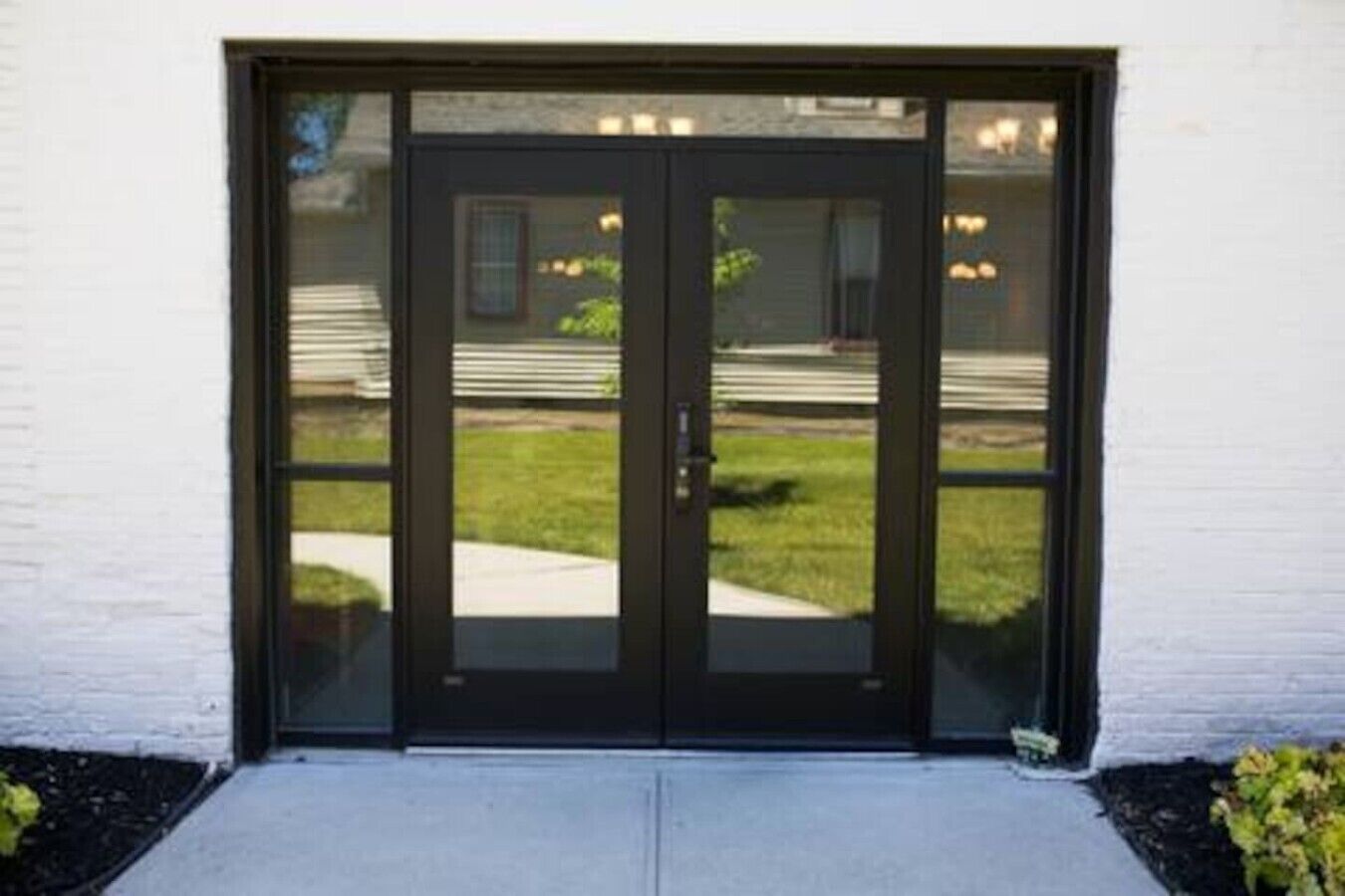 A double door with a glass panel, leading to a building with a white exterior wall.