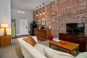 Ein Wohnzimmer mit Ziegelwand, einer Couch, einem Fernseher und einem kleinen Tisch.