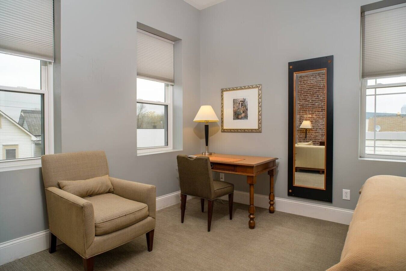 A room with a single chair, a desk, and a large mirror.