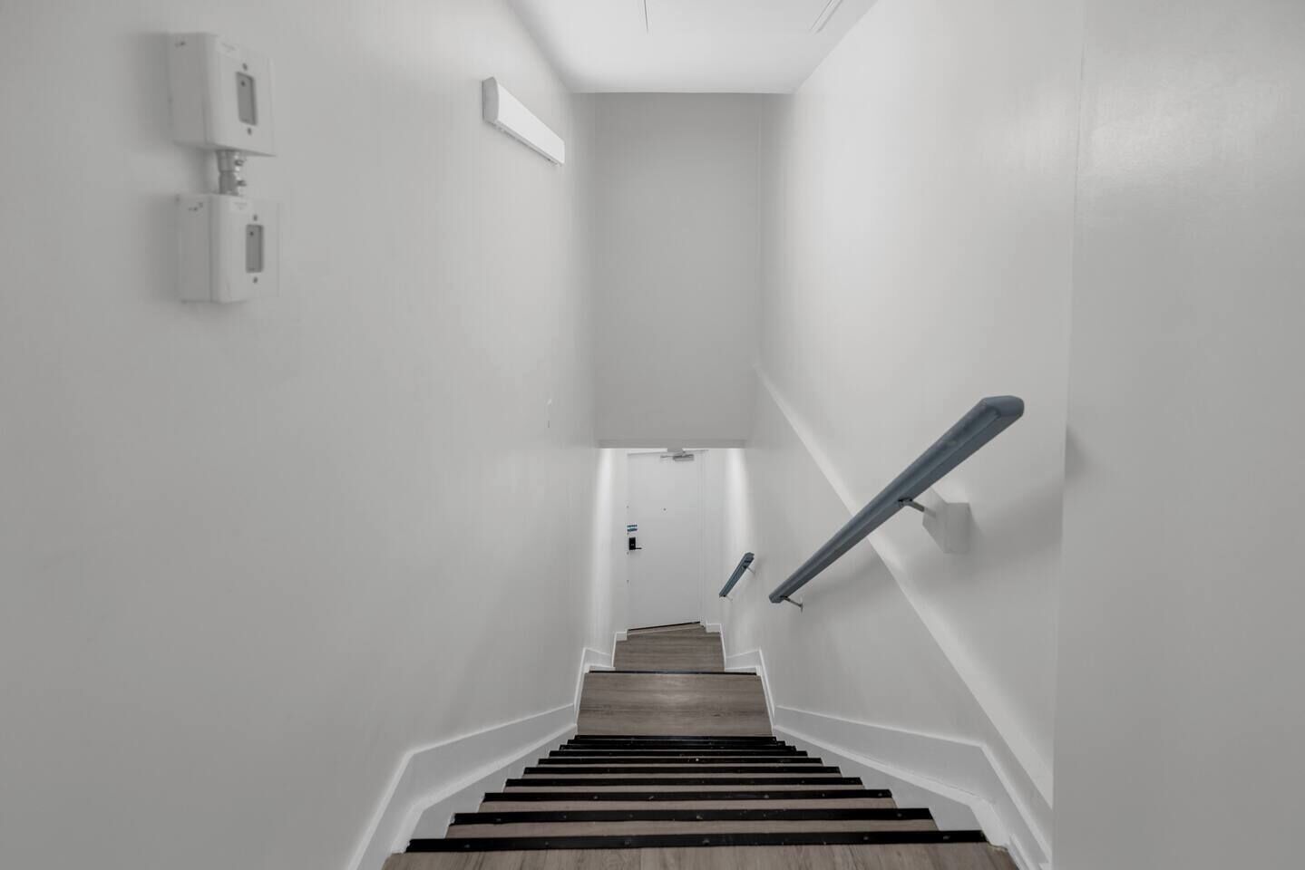 Eine Treppe mit Holzboden und Geländer, die zu einer Zwischenebene mit einer Tür führt.