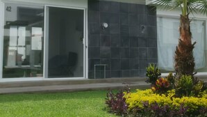 A modern building with a flat roof, large windows, and a well-maintained lawn with colorful flowers.