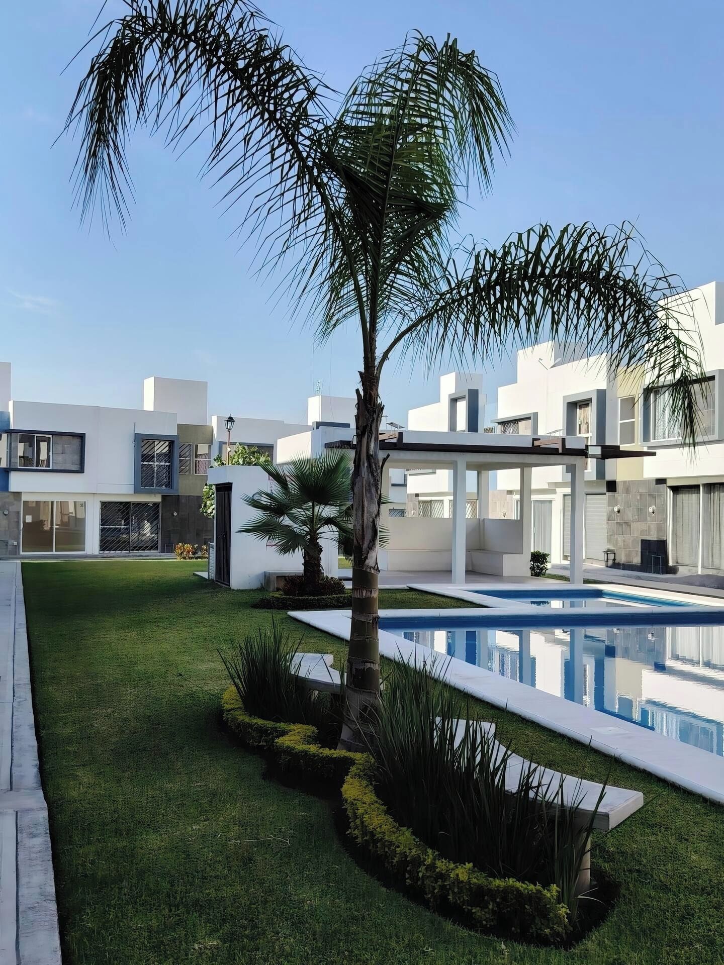 A modern residential area with a swimming pool, well-maintained lawn, and contemporary architecture.