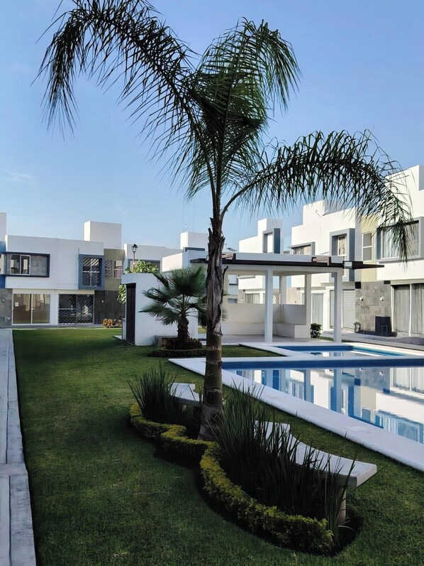 A modern residential area with a swimming pool, well-maintained lawn, and contemporary architecture.
