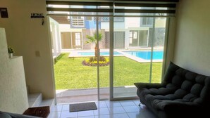 A living room with a sliding glass door leading to a pool area.