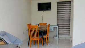 A dining area with a table and chairs, a television mounted on the wall, and a sliding door.