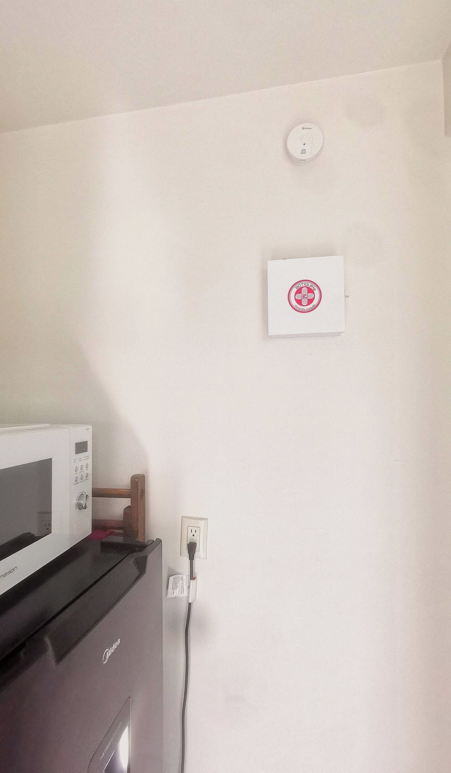 Une cuisine équipée d’un four à micro-ondes, d’une prise de courant et d’un détecteur de fumée fixé au mur.