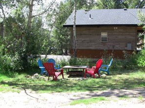 Una cabana de fusta amb una taula i cadires en una zona enjardinada.