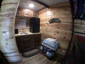Eine kleine Küche mit Holzwänden, einem Kühlschrank, einer Spüle und einem Teppich.