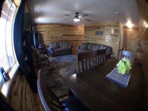A cozy cabin interior with a dining table, two sofas, and a ceiling fan. - Aspen Hideaway +Hot Tub+15 min from Yellowstone (Island Park)