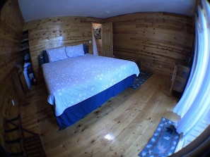 A room with a bed, wooden walls, and a door leading to another room. - Aspen Hideaway +Hot Tub+15 min from Yellowstone (Island Park)