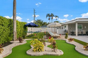 A backyard with a hammock, a small play area, and a patio with outdoor furniture. - Elegant 5BR Retreat- Pickleball + Mini golf + Pool (Bradenton)