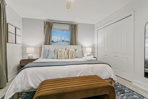 A bedroom with a bed, bedside lamps, a bench, a window with curtains, and a wardrobe. - Elegant 5BR Retreat- Pickleball + Mini golf + Pool (Bradenton)