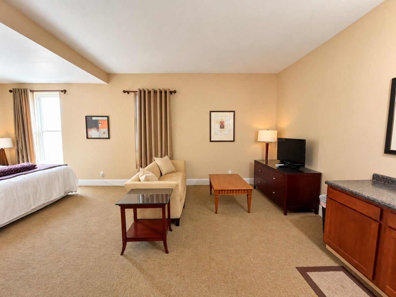 Ein Hotelzimmer mit Bett, Sofa, einem kleinen Tisch, einem Fernseher und einem Schrank.