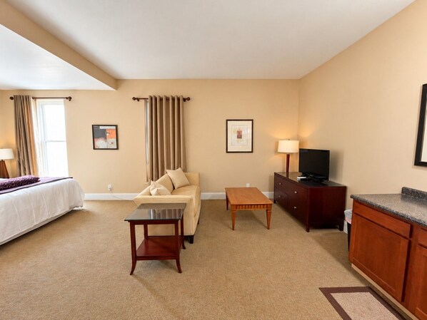 Ein Hotelzimmer mit Bett, Sofa, einem kleinen Tisch, einem Fernseher und einem Schrank.