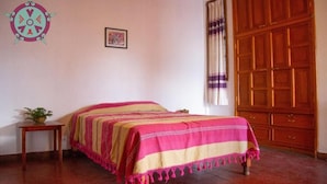 Una camera da letto con un letto, un armadio in legno, un tavolino con una pianta e un addobbo a parete.