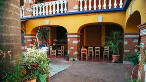 Un cortile con pavimento in mattoni, piante in vaso e mobili in legno.