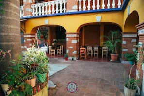 A courtyard with a brick floor, potted plants, and wooden furniture. - Casa Lua Oaxaca Comfort y Cultura (MEXICO)