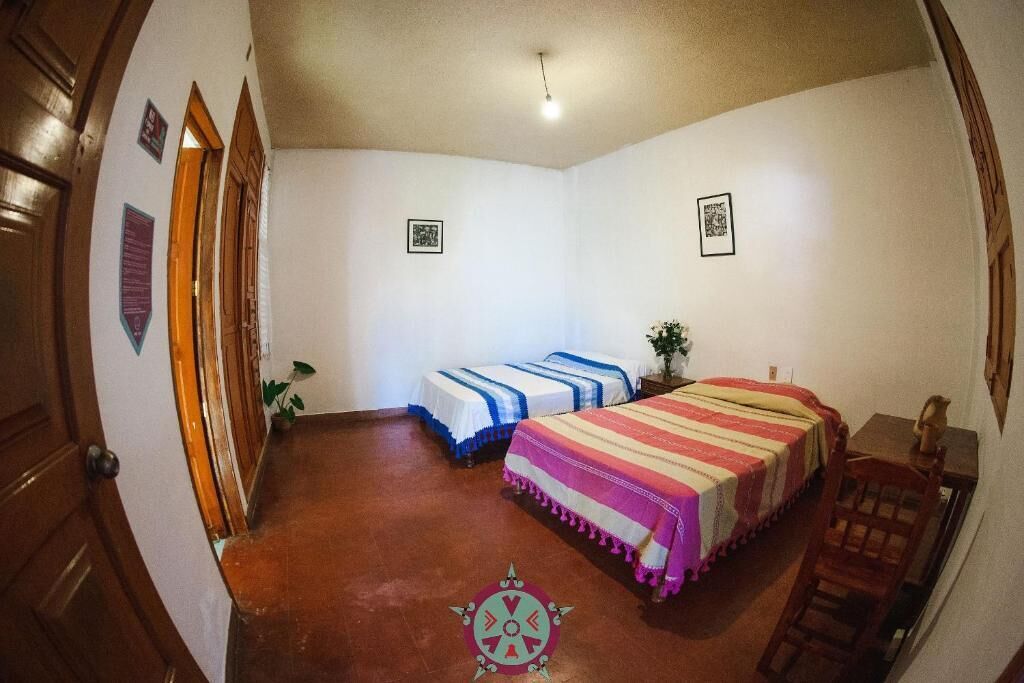 A room with two beds, a wooden door, and a small table.