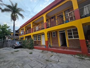 A two-story building with balconies, a car parked in front, and a palm tree. - Casa Lua Oaxaca Comfort y Cultura (MEXICO)