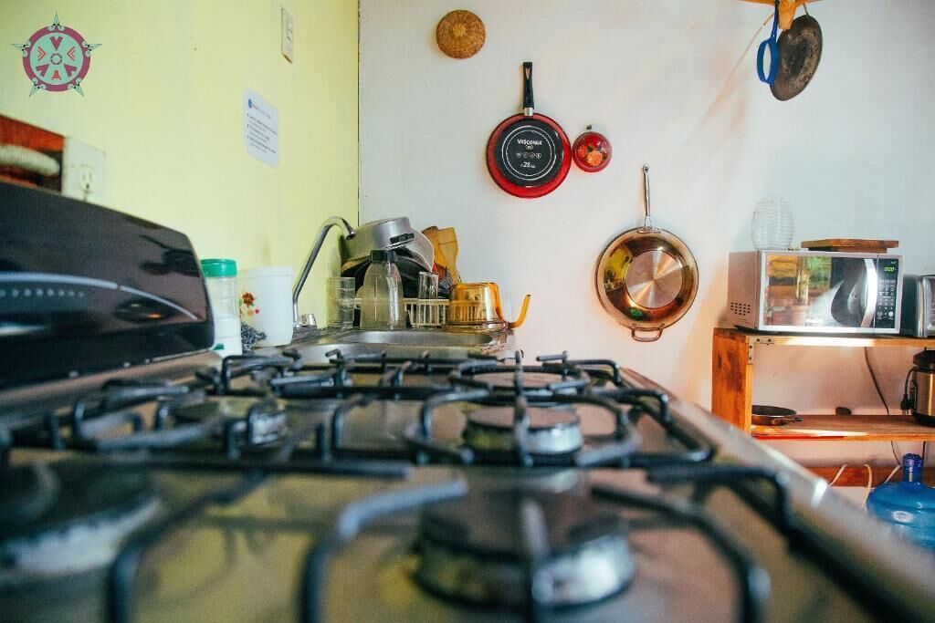 Een keuken met een gasfornuis, pannen, een magnetron en een houten plank.