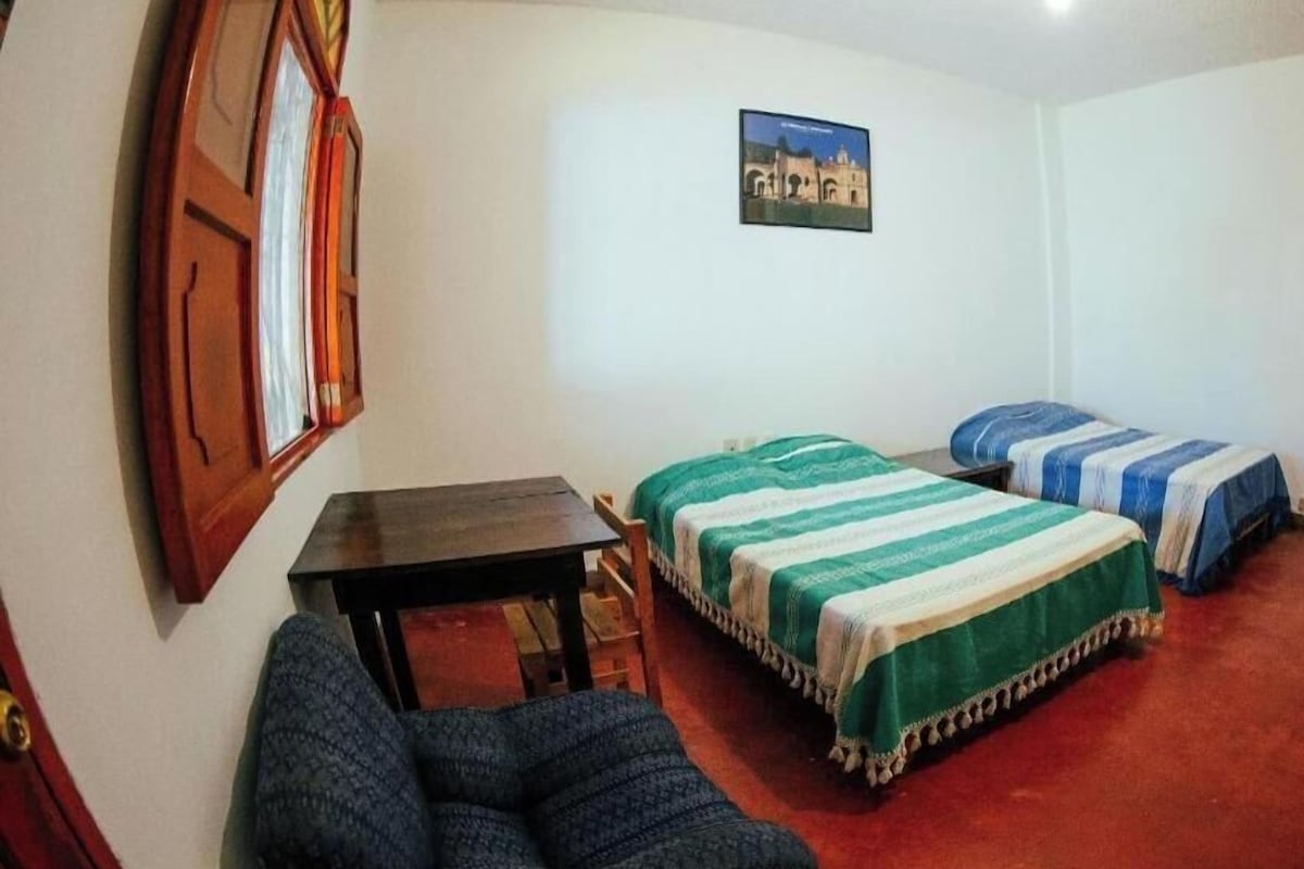 Una habitació amb dos llits, una taula petita i una cadira.