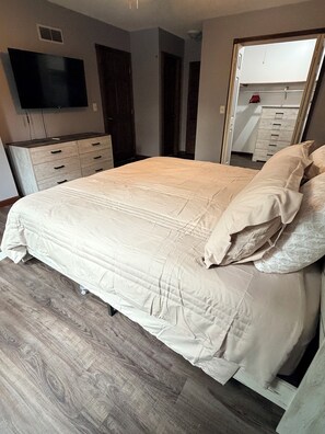 Una camera da letto con un letto grande, una cassettiera, un televisore e uno specchio.