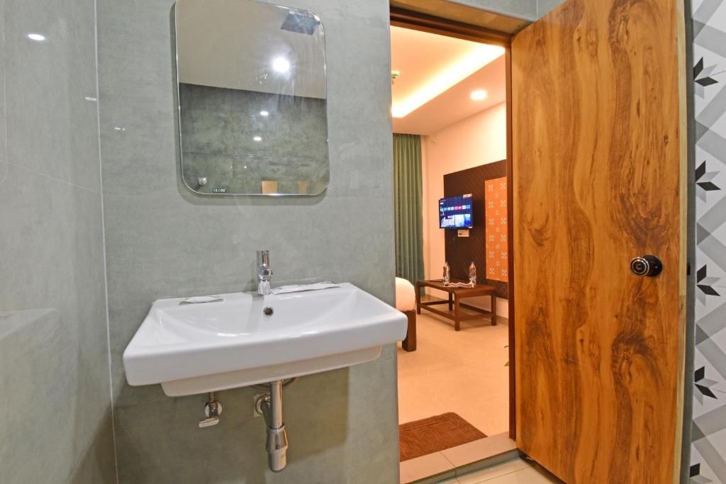 A bathroom with a white sink, a mirror, and a wooden door.