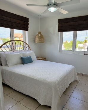 A bedroom with a bed, a ceiling fan, a hanging light fixture, and windows with blinds. - Casa Tortuga Your Relaxing Bonaire Escape Steps from Diving & Island Adventure (Kralendijk)