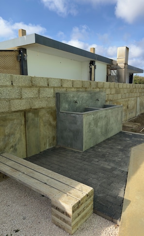 Ein Sitzbereich im Freien aus Beton mit einer Bank und einem Wasserspiel.