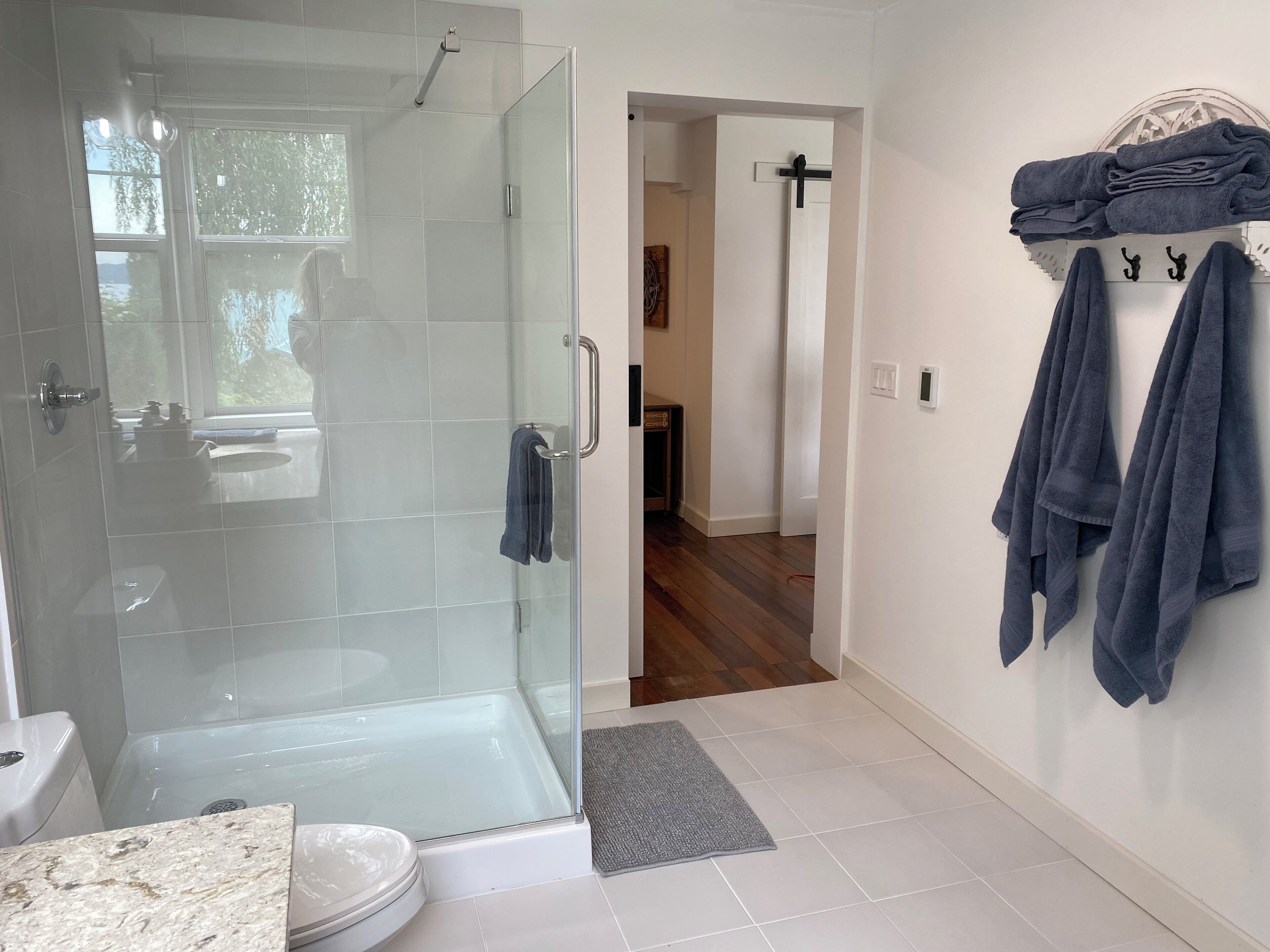 A modern bathroom with a glass-enclosed shower, a toilet, and a towel rack with folded towels.