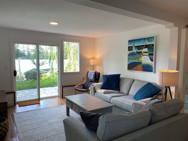 A modern living room with a sofa, coffee table, and a painting on the wall.
