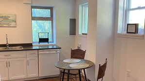 Eine Küche mit Esstisch, Stühlen und einem Fenster mit Blick auf Bäume.