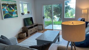 A living room with a sofa, a coffee table, a TV on a wooden stand, a lamp, and a painting on the wall.