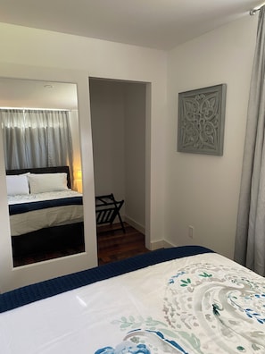 Un dormitorio con cama, una silla, una puerta que da a otra habitación y un adorno en la pared.